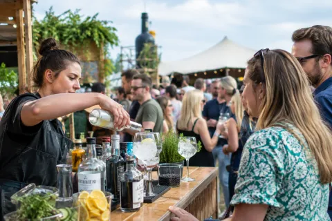 Barkeeper schenkt gin-tonic in groot glas voor juichend festivalpubliek buiten