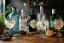 Verschillende ginflessen en drie gin-tonic glazen met citroen, komkommer en grapefruit garnituur