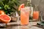 Hoog glas met roze Paloma cocktail, ijs en grapefruitpartje op rand