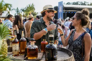 Man en vrouw toasten met rumglazen bij houten vat en rumbottels op buitenfestival