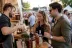 Barman schenkt whiskey in glazen voor twee bezoekers bij kraam op buitenfestival