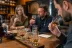 Mensen proeven whisky aan houten tafel, drie glazen whisky op proefplank, notities visible